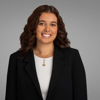 Portrait of Kenza Idrissi Janati, smiling, with long, curly hair, wearing a dark jacket.